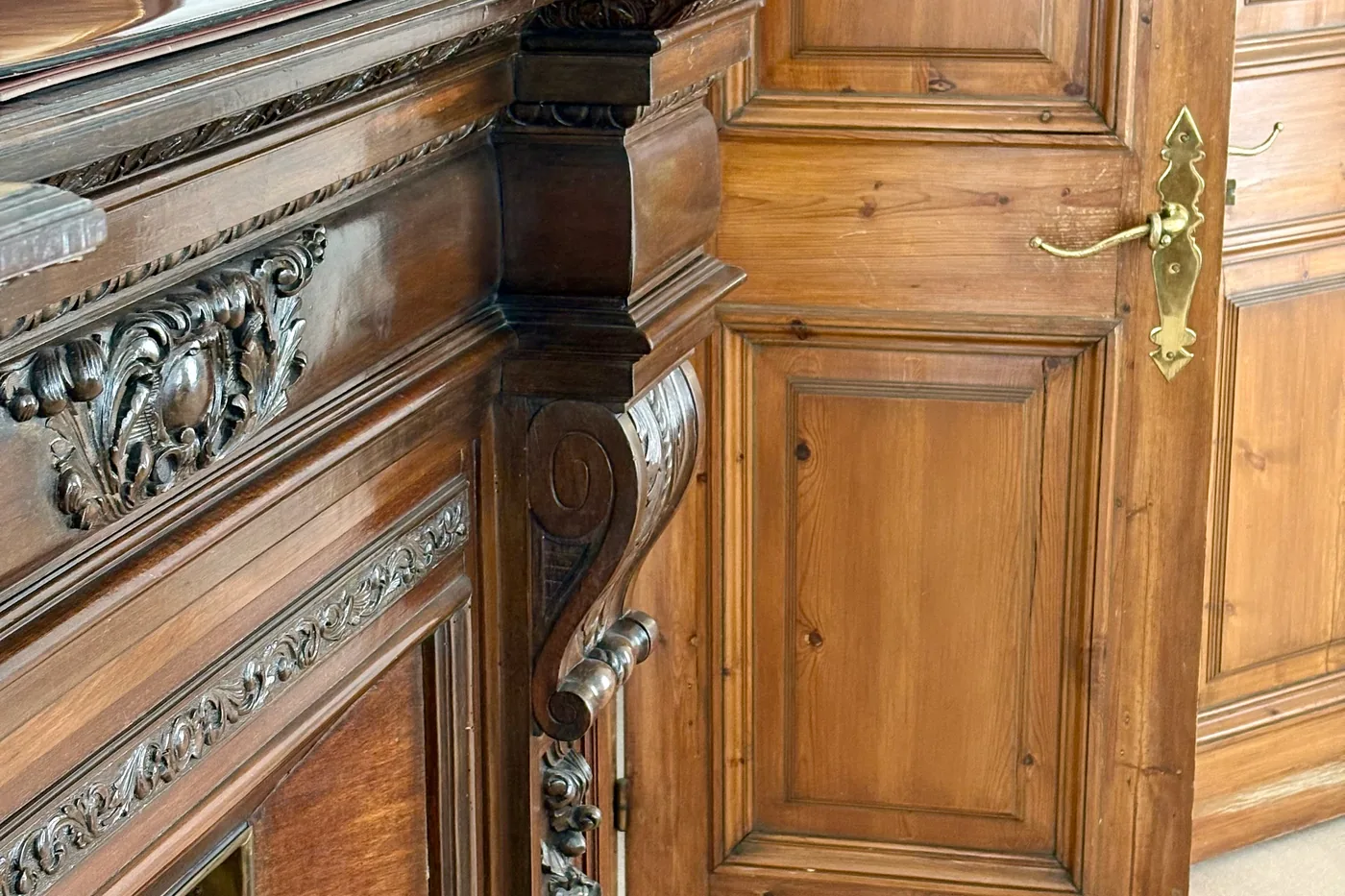 Detall de la talla de fusta de la llar de foc i del pany de llautó de la porta
