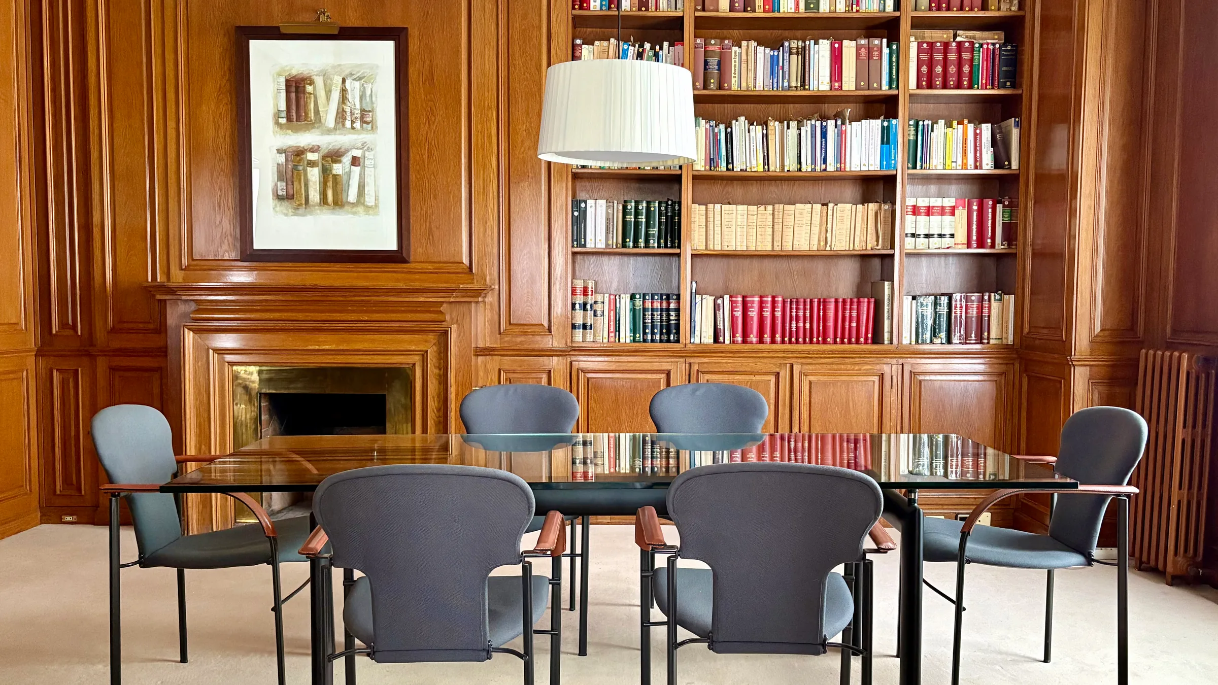 Sala de reunions amb biblioteca de fusta, llar de foc i taula de reunions